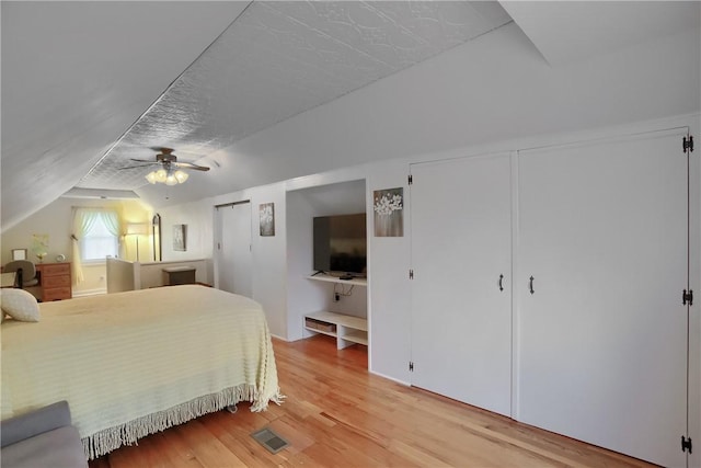 bedroom with lofted ceiling, a textured ceiling, ceiling fan, and light wood-type flooring