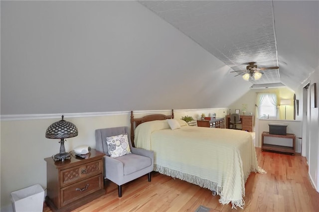 bedroom with a textured ceiling, ceiling fan, vaulted ceiling, and light hardwood / wood-style flooring