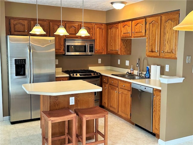 kitchen with pendant lighting, a center island, a kitchen bar, appliances with stainless steel finishes, and sink