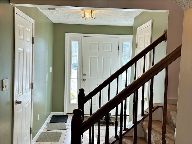 tiled foyer entrance featuring a textured ceiling and a healthy amount of sunlight