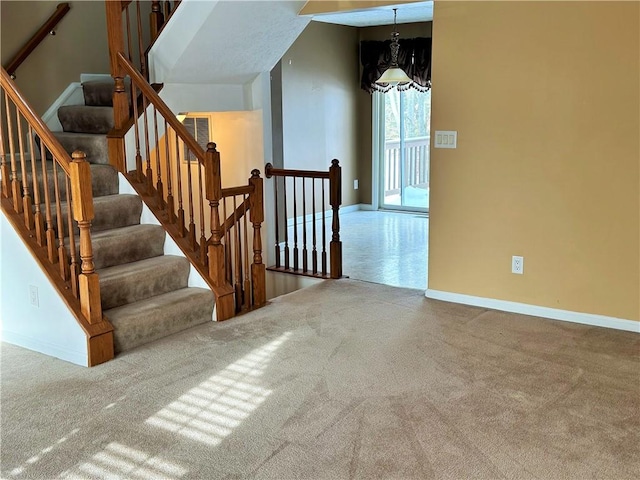 stairs with an inviting chandelier and carpet floors