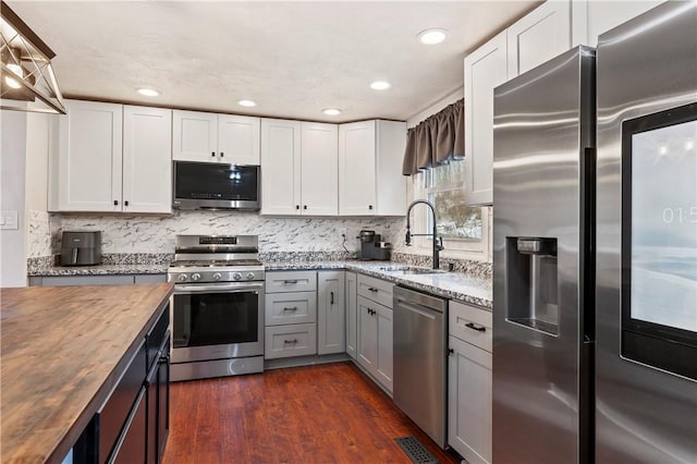 kitchen with wooden counters, stainless steel appliances, sink, and white cabinetry