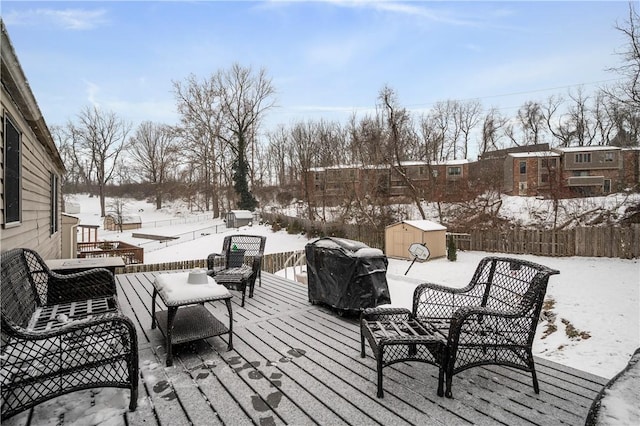 snow covered deck featuring area for grilling and a shed