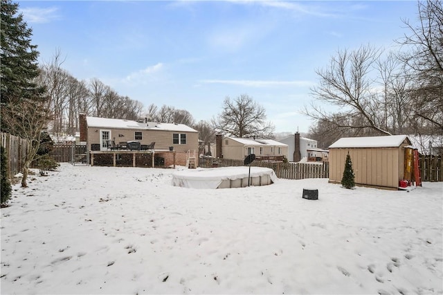 snow covered house featuring a storage shed