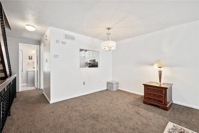 empty room with an inviting chandelier and carpet flooring