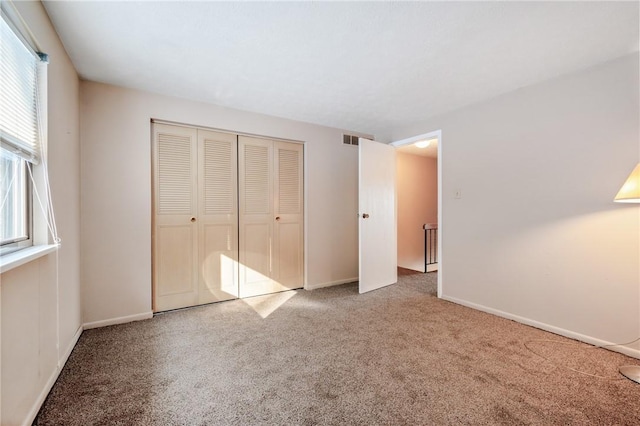 unfurnished bedroom featuring carpet floors, a closet, and multiple windows