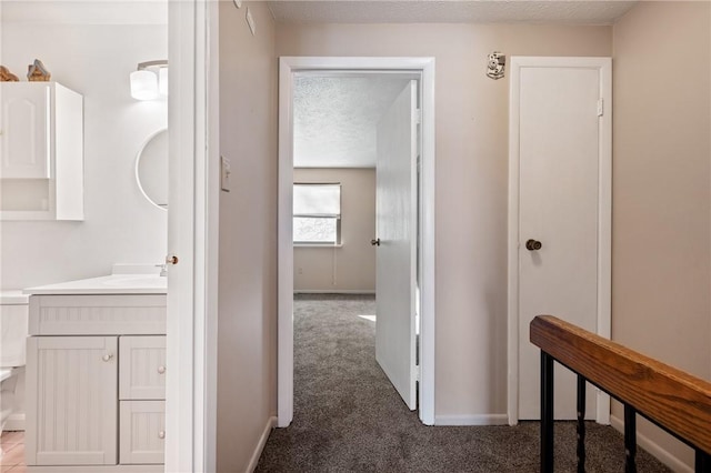 hall featuring sink, carpet floors, and a textured ceiling