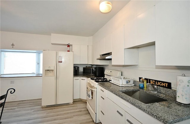 kitchen featuring sink, white appliances, dark stone countertops, and white cabinets