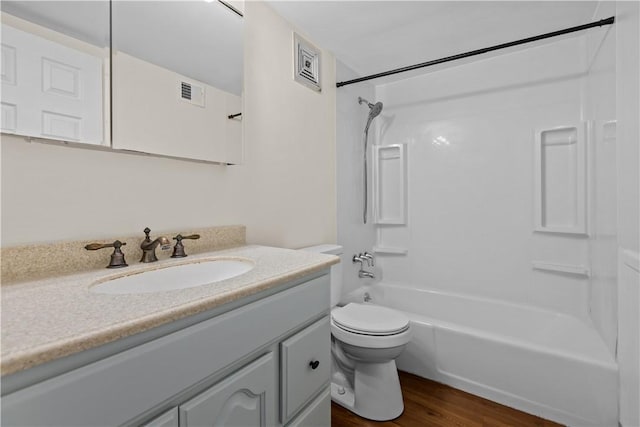 full bathroom featuring washtub / shower combination, hardwood / wood-style floors, vanity, and toilet