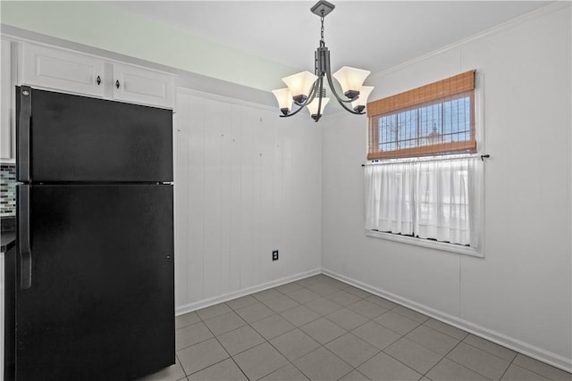 unfurnished dining area with light tile patterned flooring, ornamental molding, and a chandelier