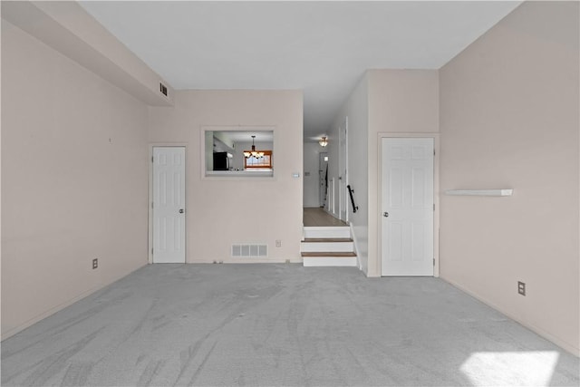 carpeted spare room featuring a chandelier