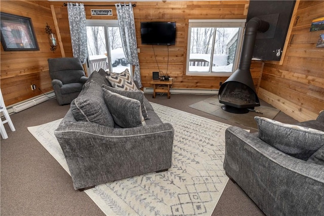 living room with dark colored carpet, wooden walls, a wood stove, and a baseboard heating unit