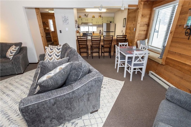 carpeted living room with wooden walls and a baseboard heating unit