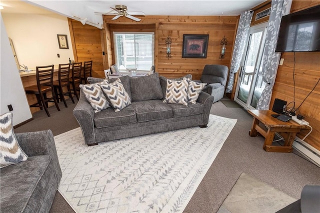 carpeted living room with beam ceiling, ceiling fan, and wooden walls