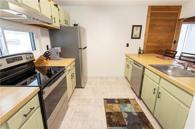 kitchen with stainless steel appliances, green cabinetry, sink, and wood counters