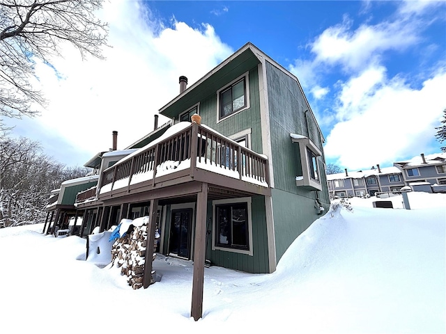 snow covered back of property featuring a deck