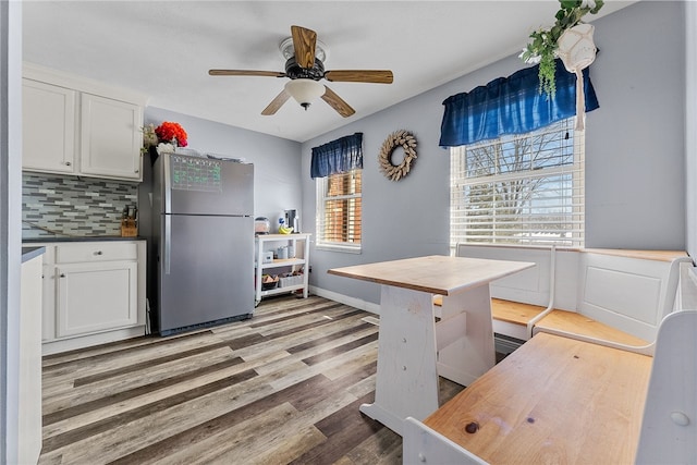 kitchen featuring white cabinets, stainless steel fridge, light hardwood / wood-style flooring, and tasteful backsplash