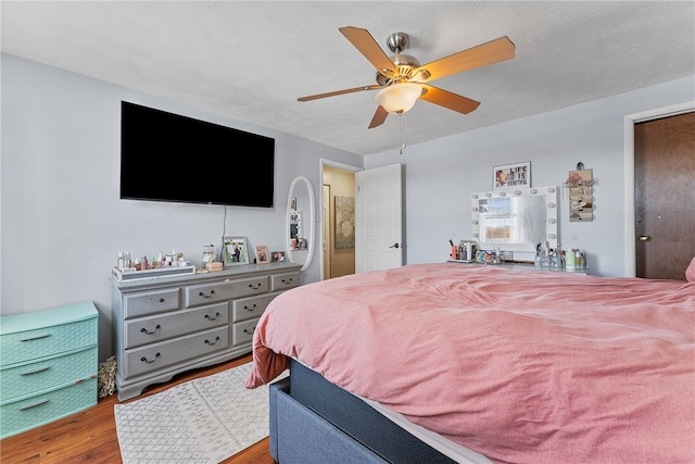 bedroom with a textured ceiling, ceiling fan, and light wood-type flooring