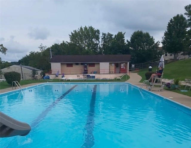 view of pool with a water slide and a patio