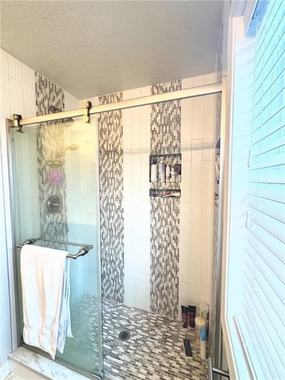 bathroom with a shower with door and a textured ceiling