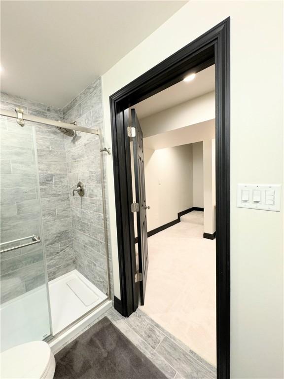 bathroom with a shower with shower door and toilet