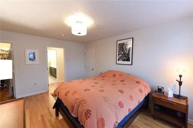 bedroom with ensuite bathroom and light hardwood / wood-style floors