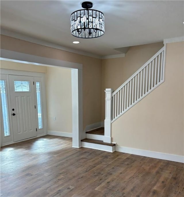 foyer with hardwood / wood-style flooring, ornamental molding, and a chandelier