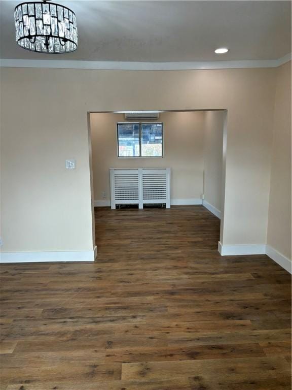 empty room with ornamental molding, a chandelier, and dark hardwood / wood-style flooring