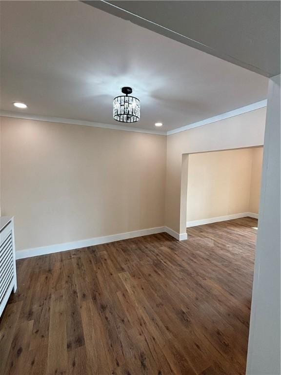 empty room featuring an inviting chandelier, ornamental molding, and dark hardwood / wood-style flooring