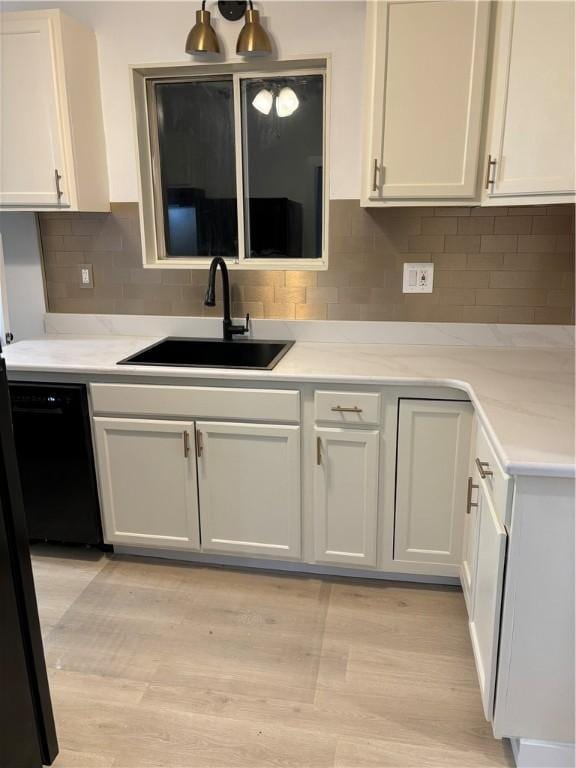 kitchen featuring black dishwasher, sink, and white cabinets