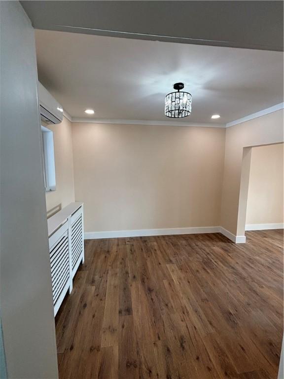 interior space with crown molding, dark wood-type flooring, and a wall unit AC