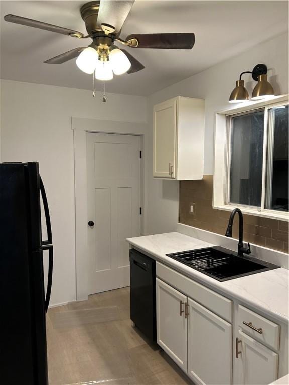 kitchen featuring sink, tasteful backsplash, black appliances, light hardwood / wood-style flooring, and white cabinets