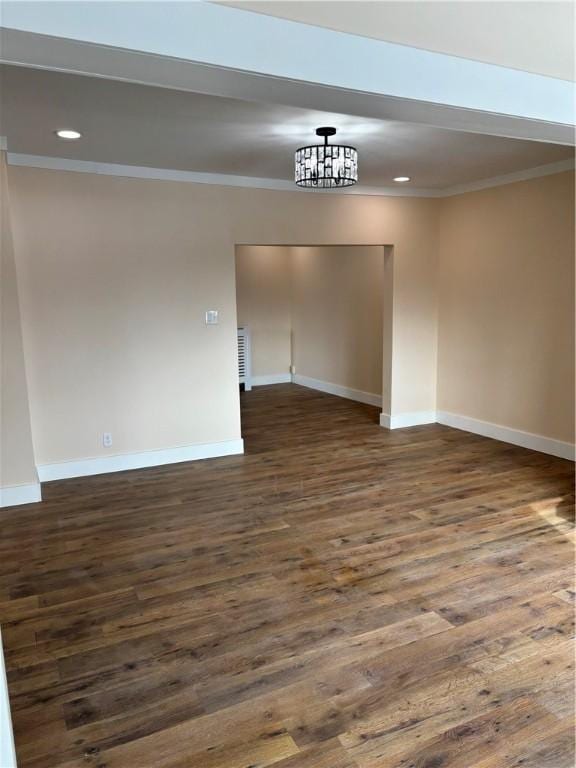 empty room with crown molding and dark wood-type flooring