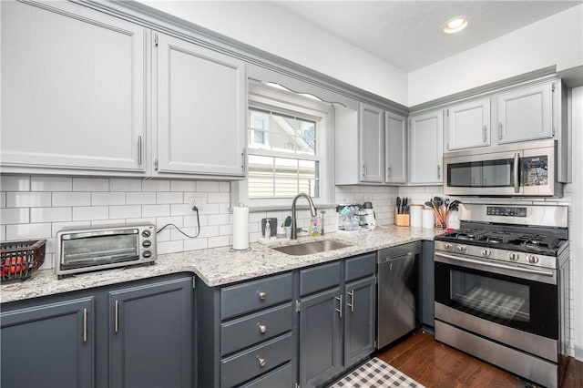 kitchen featuring appliances with stainless steel finishes, gray cabinetry, dark hardwood / wood-style floors, and sink