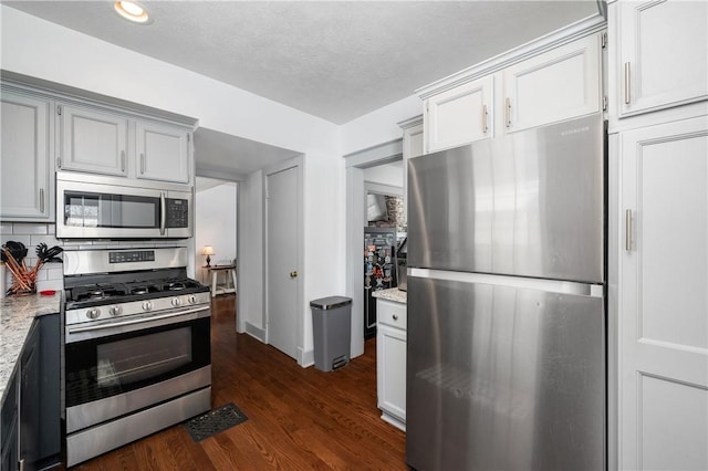 kitchen with dark hardwood / wood-style flooring, decorative backsplash, light stone counters, and appliances with stainless steel finishes