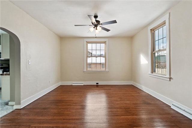 spare room featuring baseboard heating, ceiling fan, and dark wood-type flooring