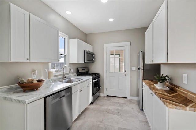 kitchen featuring sink, appliances with stainless steel finishes, light stone counters, and white cabinetry