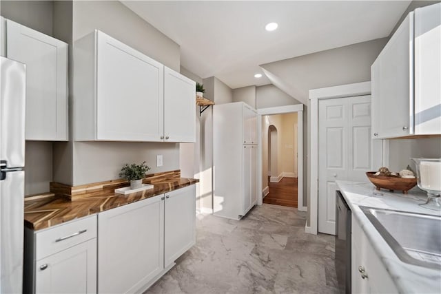 kitchen featuring dishwasher, stone countertops, white cabinetry, fridge, and sink