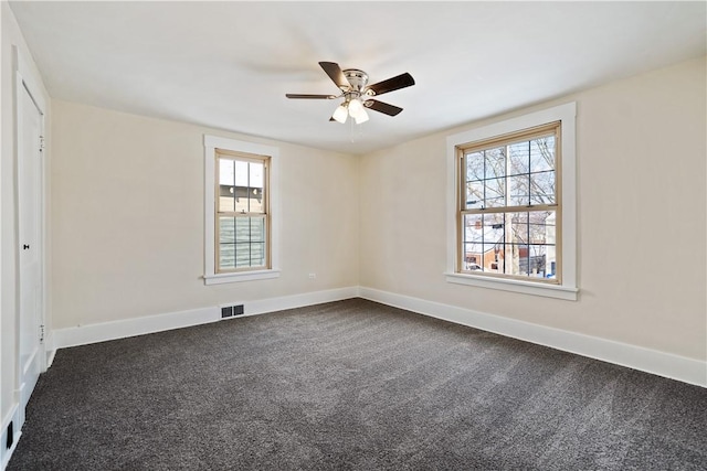 empty room with dark colored carpet and ceiling fan