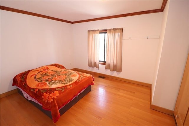 bedroom with hardwood / wood-style flooring and crown molding