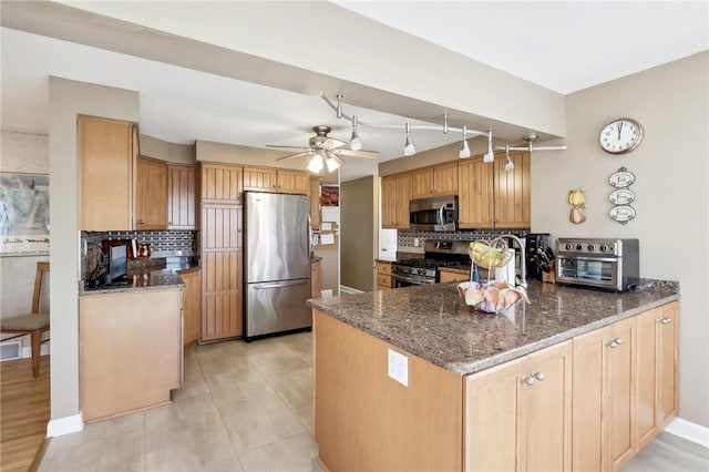 kitchen featuring stainless steel appliances, light tile patterned flooring, kitchen peninsula, decorative backsplash, and dark stone counters