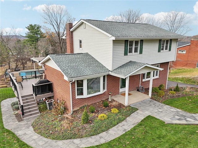 front of property with a patio area, central AC unit, a front lawn, and a wooden deck