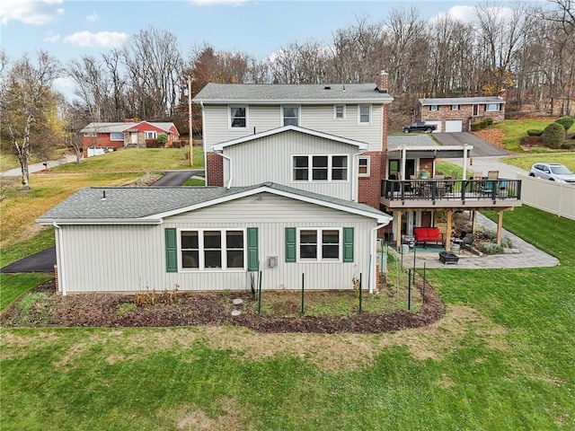 back of property with a patio, a wooden deck, and a lawn