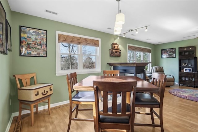 dining space with light hardwood / wood-style flooring and rail lighting