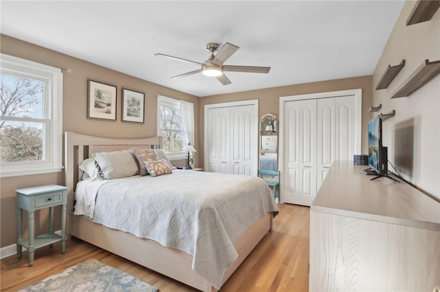 bedroom featuring multiple closets, ceiling fan, and light wood-type flooring