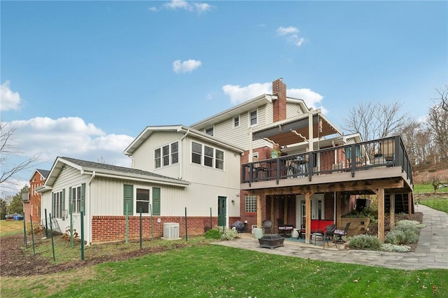 rear view of house featuring a patio area, a deck, central AC unit, a lawn, and a fire pit