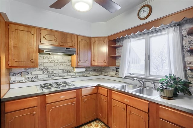 kitchen with sink, stainless steel gas stovetop, decorative backsplash, and ceiling fan