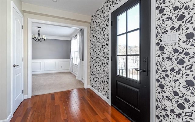 entryway with dark hardwood / wood-style flooring, crown molding, and a notable chandelier