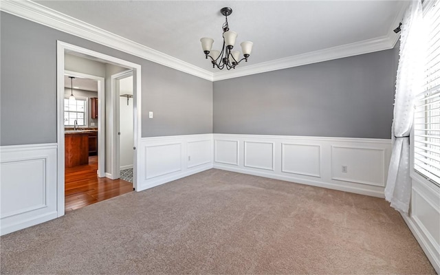 carpeted spare room featuring ornamental molding, an inviting chandelier, and sink