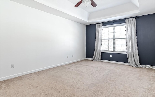 unfurnished room featuring ceiling fan, light carpet, and a raised ceiling